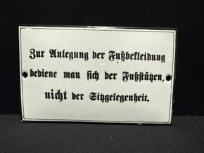 Anlegung der Fußbekleidung….. - Gewölbtes Hinweisschild (Um 1920)